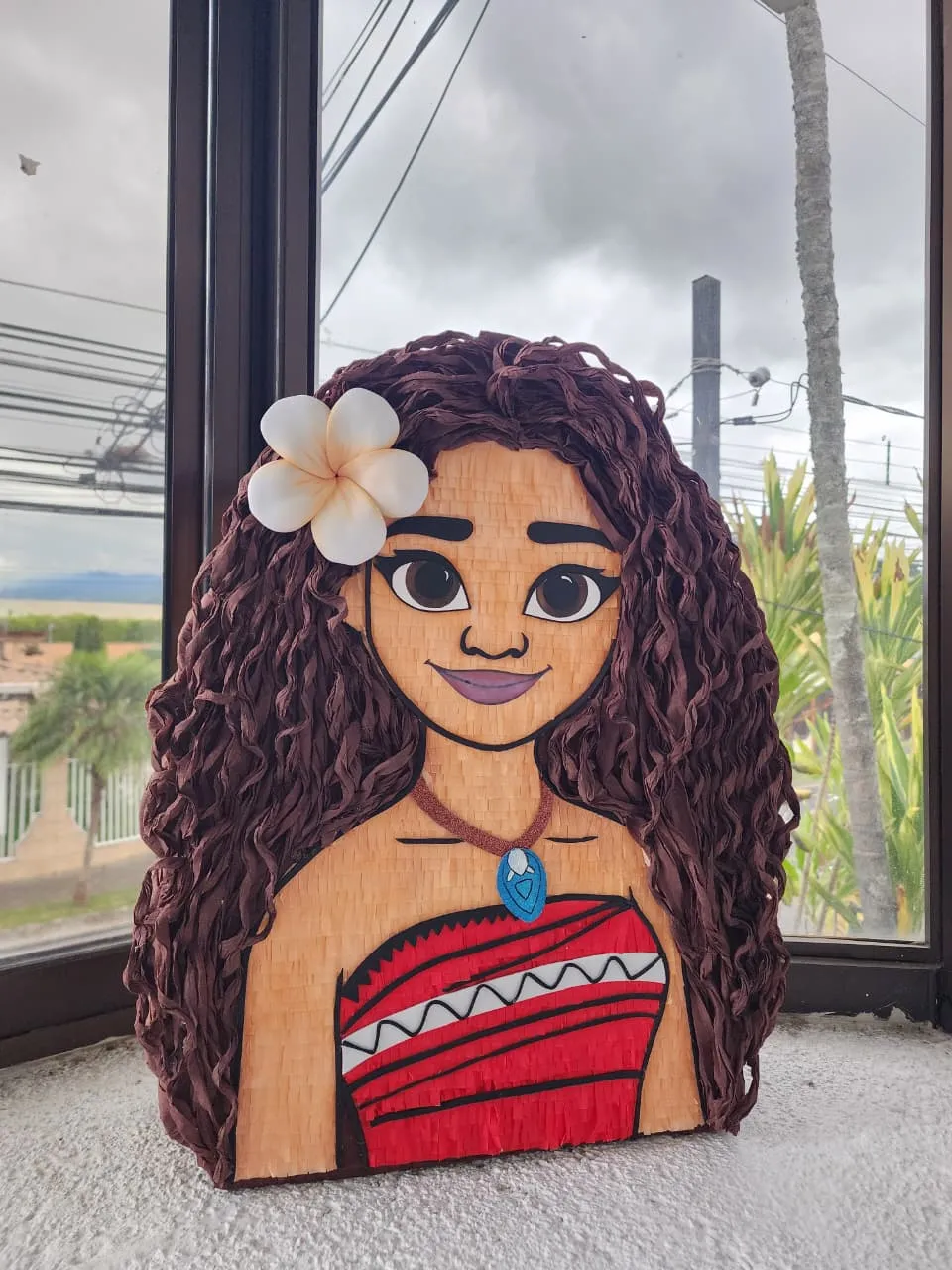 Piñata de Moana con cabello rizado de papel y flor en el pelo